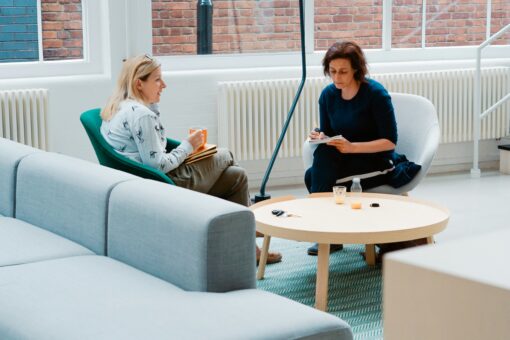 Two women having a one-on-one coaching session in a modern, light-filled office.