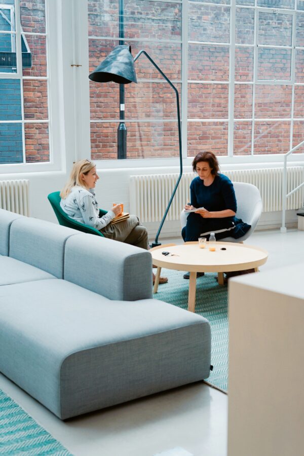 Leadership Consulting Two women having a one-on-one coaching session in a modern, light-filled office.
